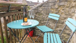 A table with a bottle and two glasses, a plate with food, and two chairs on a wooden deck. - The Old Bakery Barn (Bakewell)