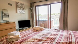 Une chambre d’hôtel avec un lit, une télévision, une commode et un balcon offrant une vue.