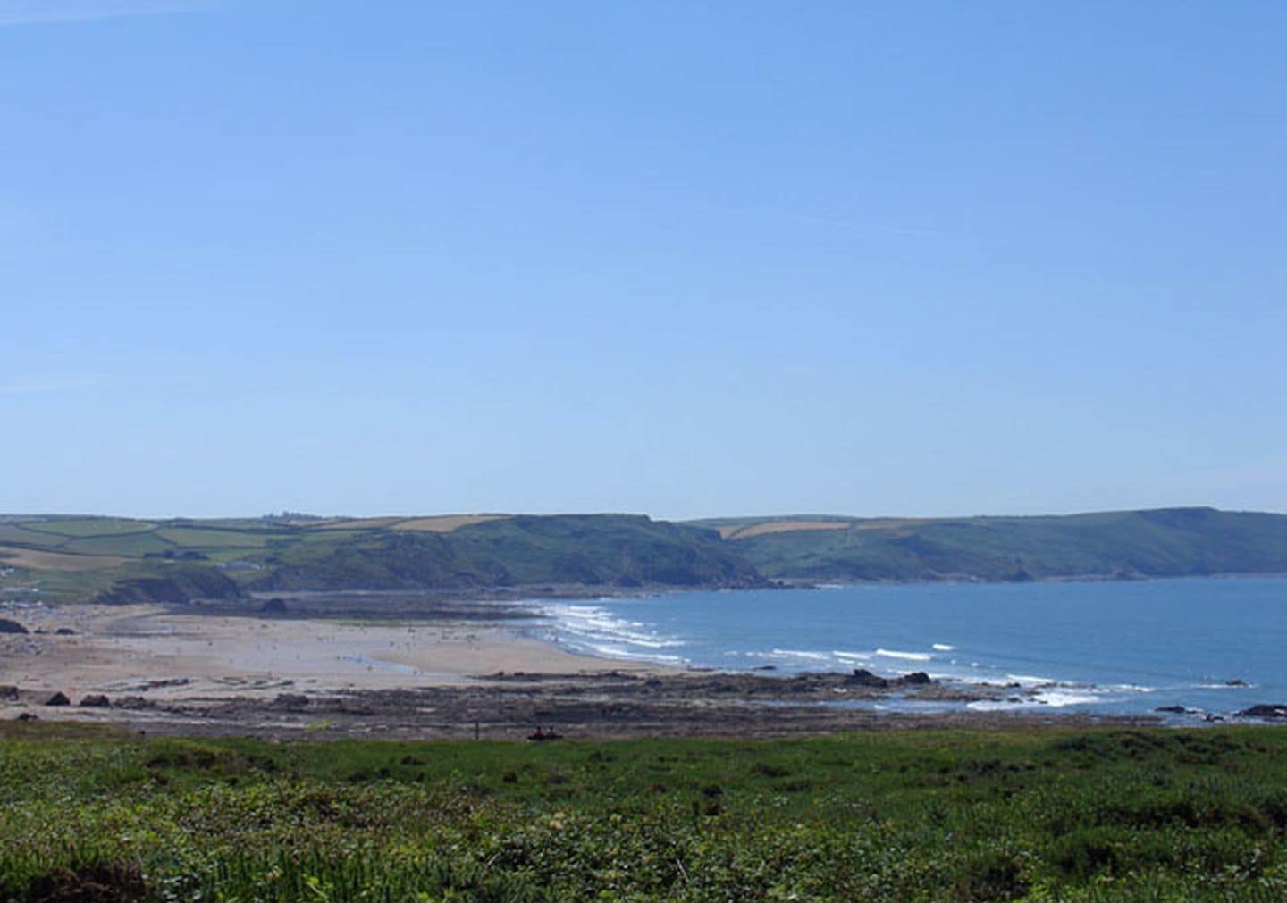 A coastal landscape with a beach, grassy areas, and cliffs.