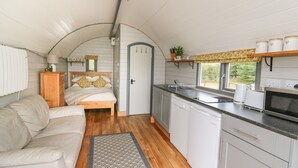 A compact, well-lit interior with a cozy bed, a kitchenette, and a small seating area.