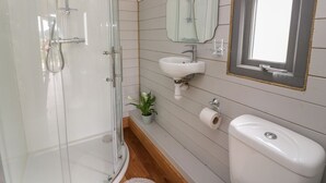 A bathroom with a glass-enclosed shower, a sink with a mirror above it, and a toilet.
