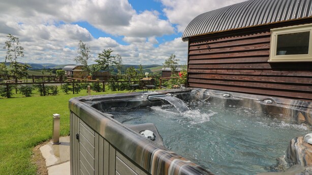 A hot tub with a wooden cabin in the background.
