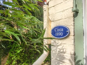 Placa azul com a inscrição 'Cerca de 1890' fixada na parede externa de um edifício.