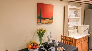 Comedor con una mesa lista para el desayuno, que incluye frutas, un hervidor y una taza.