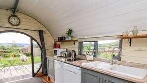 Une cuisine donnant sur la campagne, une horloge au mur et une fenêtre offrant une belle vue.