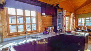 A modern kitchen with a large island, wooden cabinetry, and a window with a view of the outside. - St Hilda's Lodge (Saltburn-by-the-Sea)