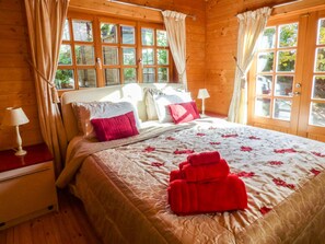 Une chambre dans une cabane en bois, avec un lit, des rideaux et une fenêtre.