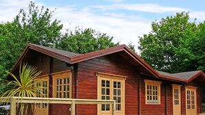 A wooden cabin with a porch, large windows, and a small deck area. - St Hilda's Lodge (Saltburn-by-the-Sea)
