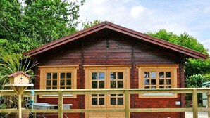 A wooden cabin with a deck, two windows, and a birdhouse. - St Hilda's Lodge (Saltburn-by-the-Sea)