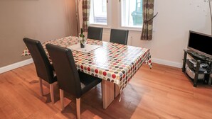 A dining area with a polka dot tablecloth, wooden chairs, a wine glass, and a TV stand. - Seahorse (Whitby)