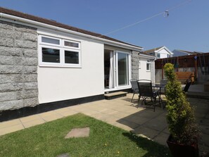 A house with a stone facade, a large sliding glass door, and a patio with a table and chairs. - 22 Trembel Road (Helston)