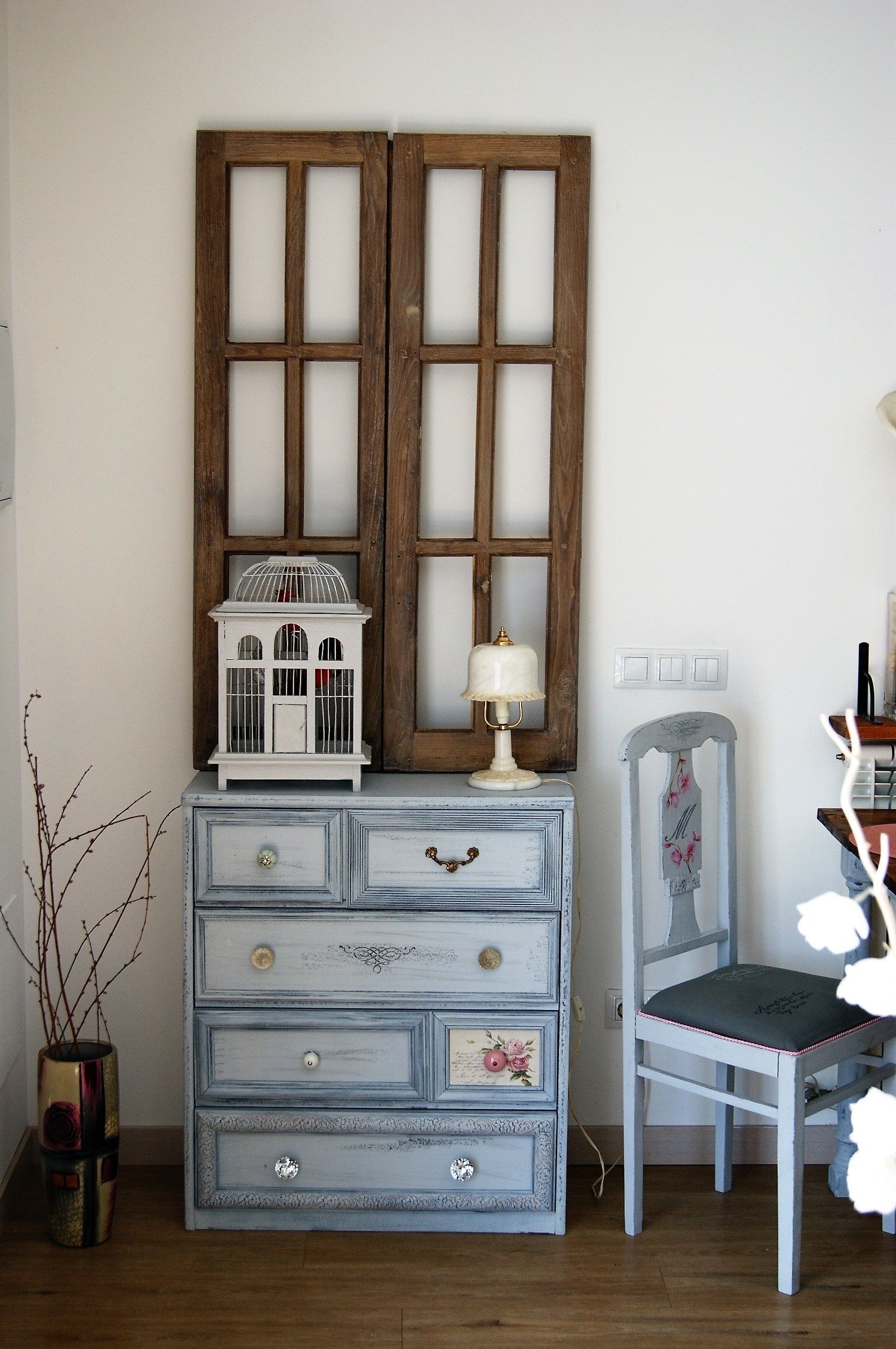 A room with a dresser, a chair, a lamp, and a decorative item on the dresser.