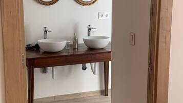 Un baño con dos lavamanos, un tocador de madera y dos espejos decorativos.