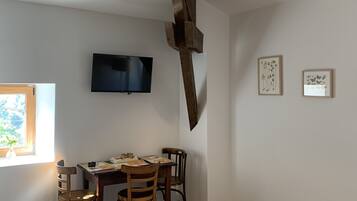 Un comedor con una mesa y sillas de madera, un televisor de pantalla plana montado en la pared, y dos cuadros enmarcados.