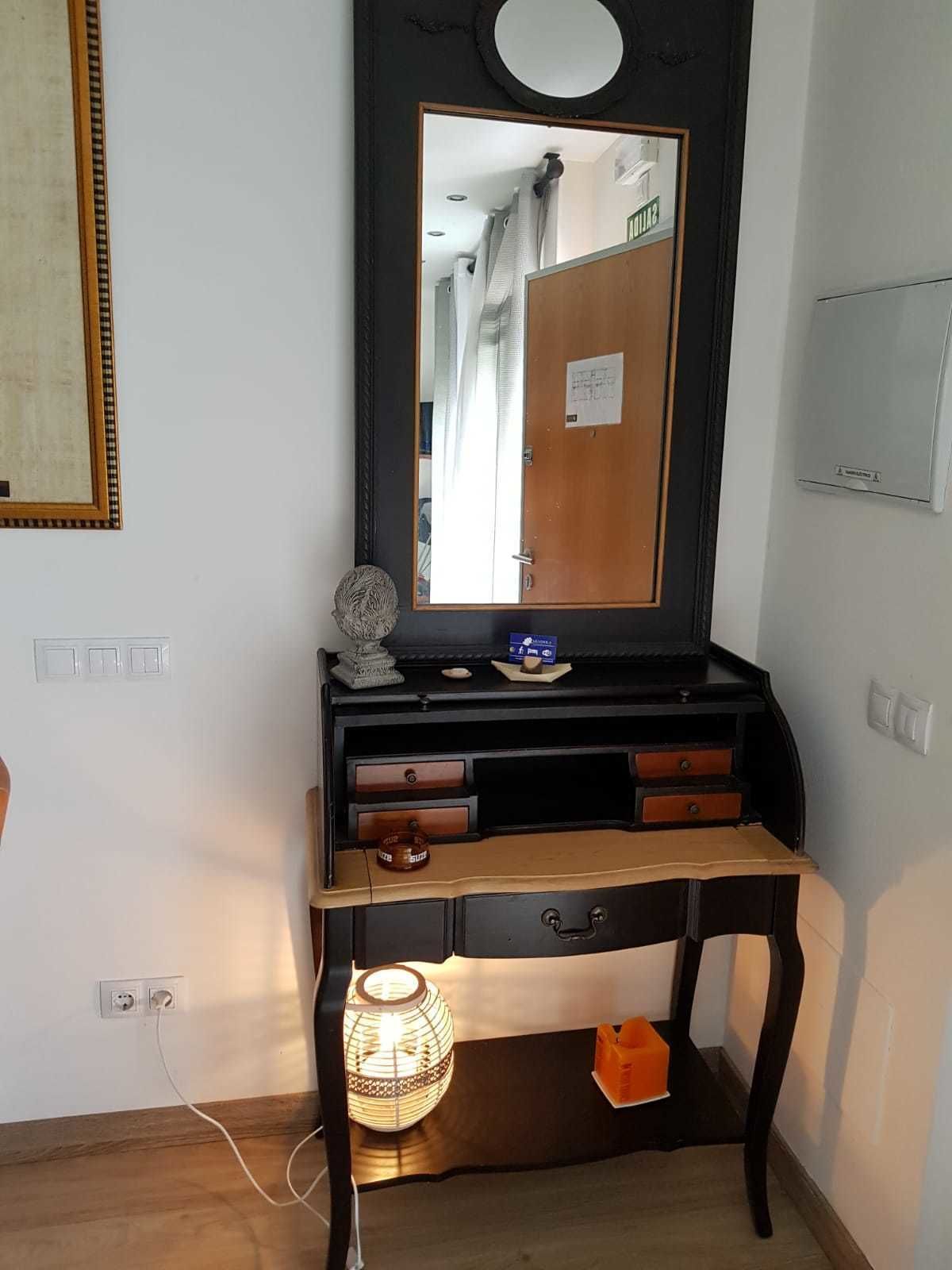 Ein Zimmer mit einem Holztischchen, einem Spiegel und einer kleinen Lampe.