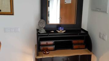 Ein Zimmer mit einem Holztischchen, einem Spiegel und einer kleinen Lampe.