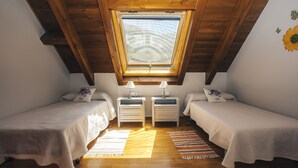 A small, cozy attic bedroom with two single beds, a skylight, wooden beams, and a simple, functional design. - Apartamentos De Montaña Mendiola (Valcarlos)