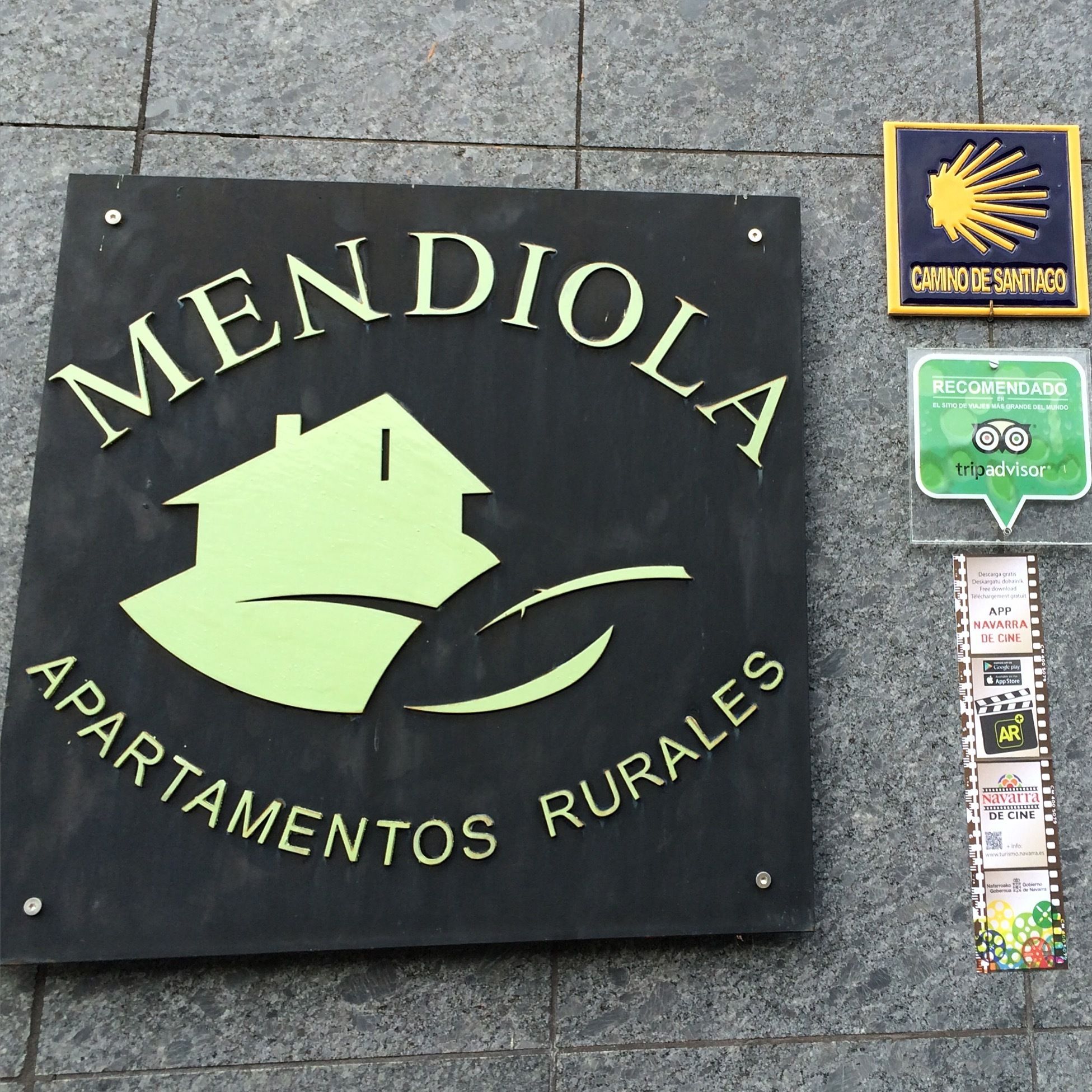 A sign for 'MENDIOLA APARTAMENTOS RURALES' with a house logo.