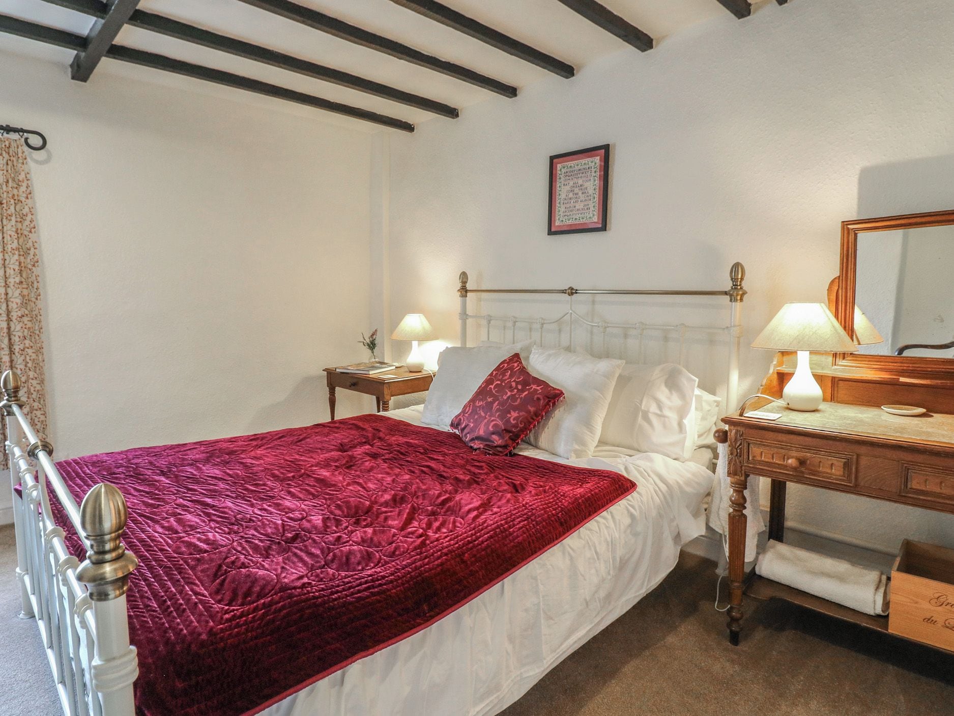 A bedroom with a bed, bedside tables, a dresser, a mirror, and a framed picture on the wall.