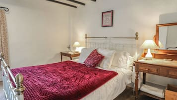 A bedroom with a bed, bedside tables, a dresser, a mirror, and a framed picture on the wall.