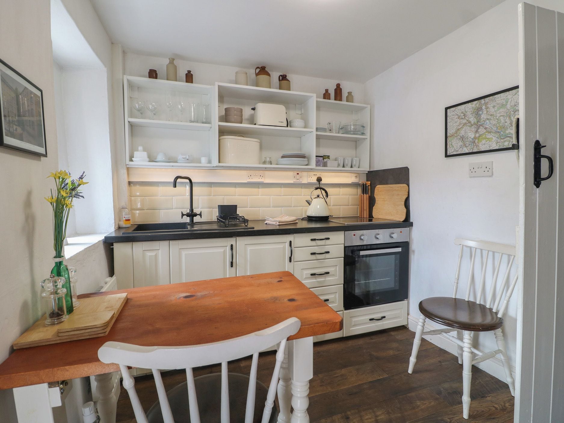A kitchen with white cabinets, a wooden table, and a white chair.