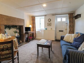 A cozy living room with a sofa, a small table, a fireplace, and a television. - The Hill (Matlock)