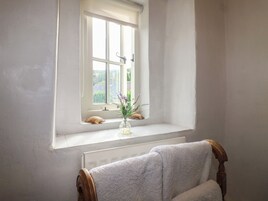 Casa de banho com janela, porta-toalhas e um pequeno vaso com flores.