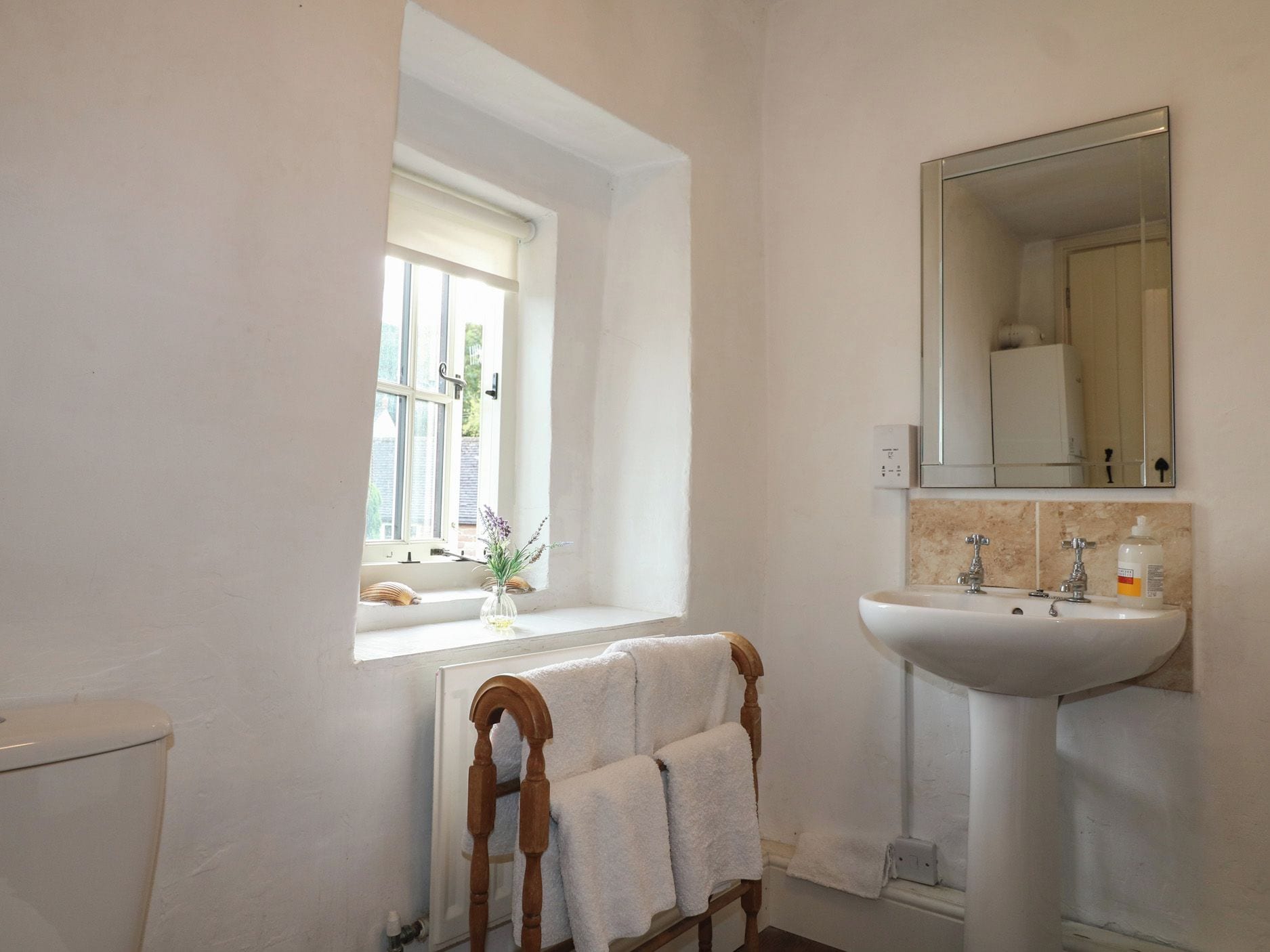 Een badkamer met een raam, een wastafel en een handdoekhouder.