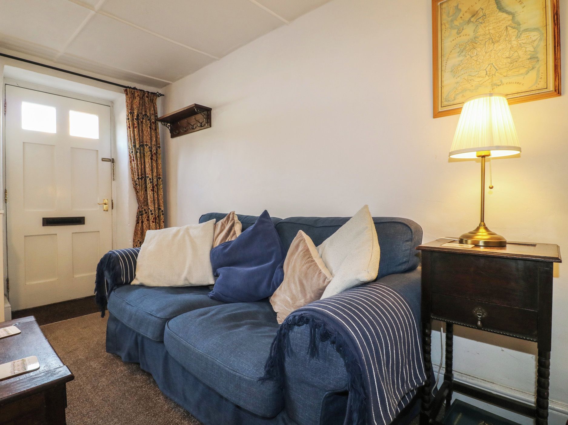 A room with a blue sofa, a lamp on a side table, and a door with a curtain.