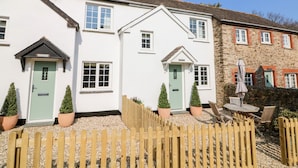 A row of white houses with green doors, a wooden fence, and potted plants. - Martin Cottage (Ilfracombe)