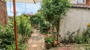 A garden pathway with potted plants and a white table.
