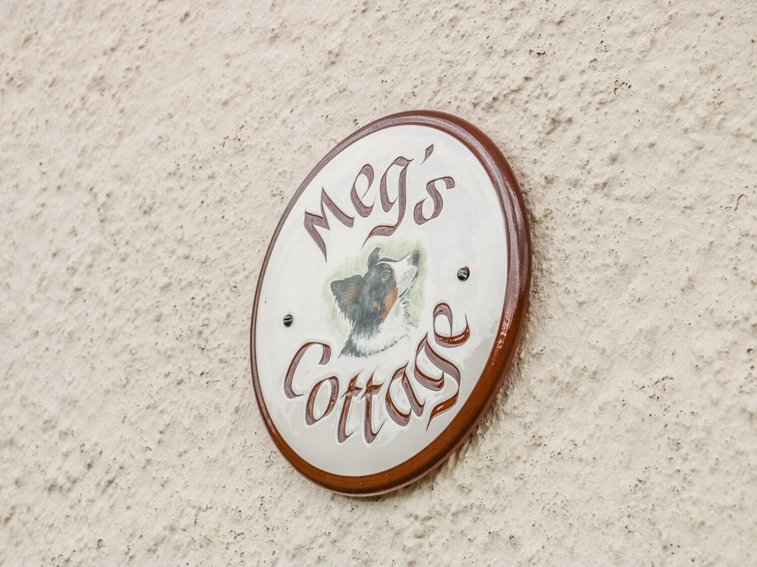 A round sign with the text "Mey's Cottage" and a dog's face.