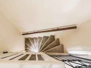 A spiral staircase with a wooden handrail and carpeted steps. - Megs Cottage (Norwich)
