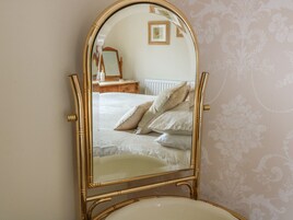 Quarto com cama, cômoda e espelho sobre suporte.