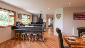 A modern kitchen with a central island, wooden stools, and a dining area with a table and chairs.