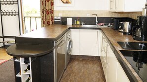A compact kitchen with a washing machine, a coffee maker, and a sink.