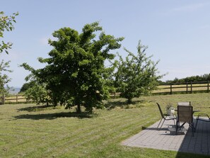 Un patio con mobiliario exterior y un gran árbol.