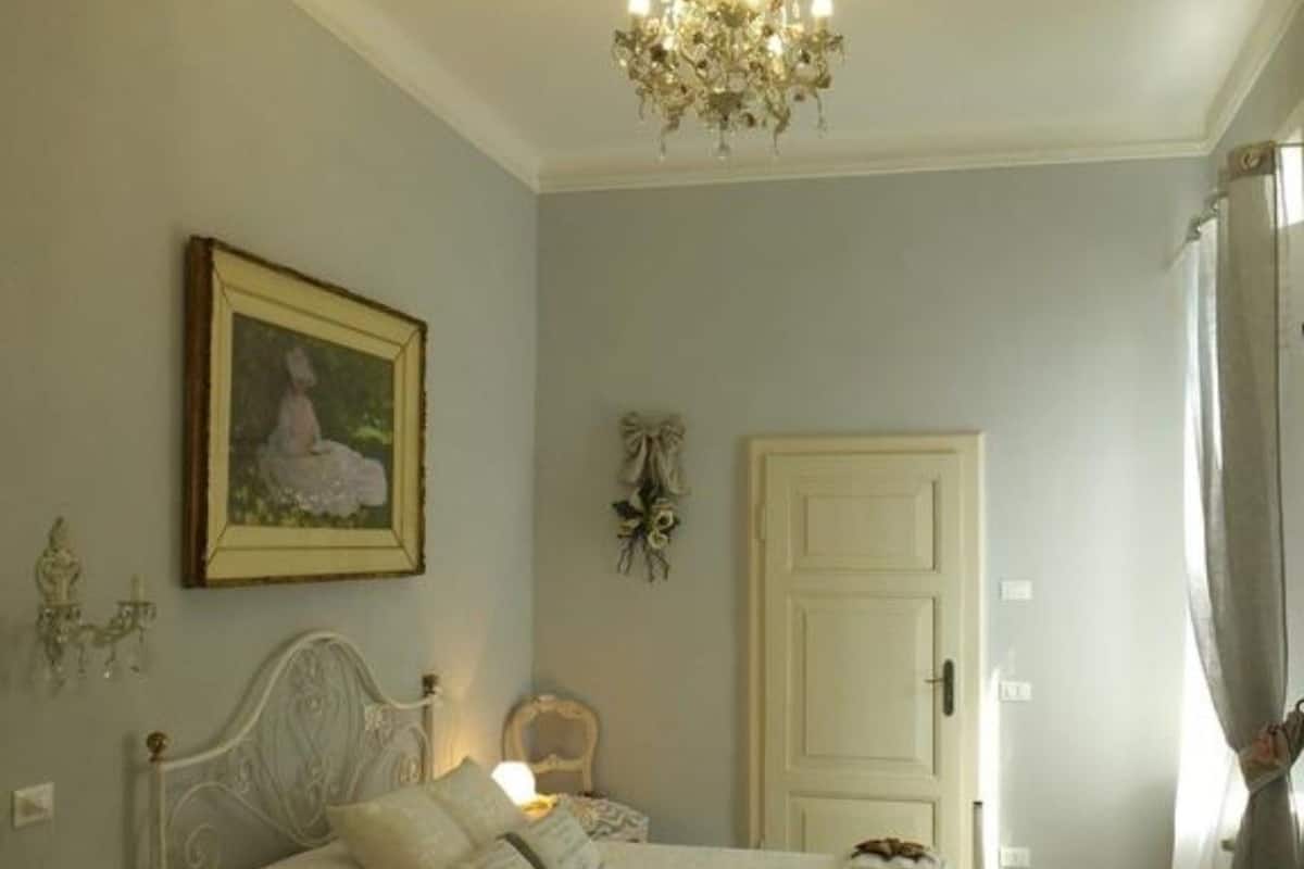 Une chambre avec deux lits, un lustre, un tableau encadré et une porte.