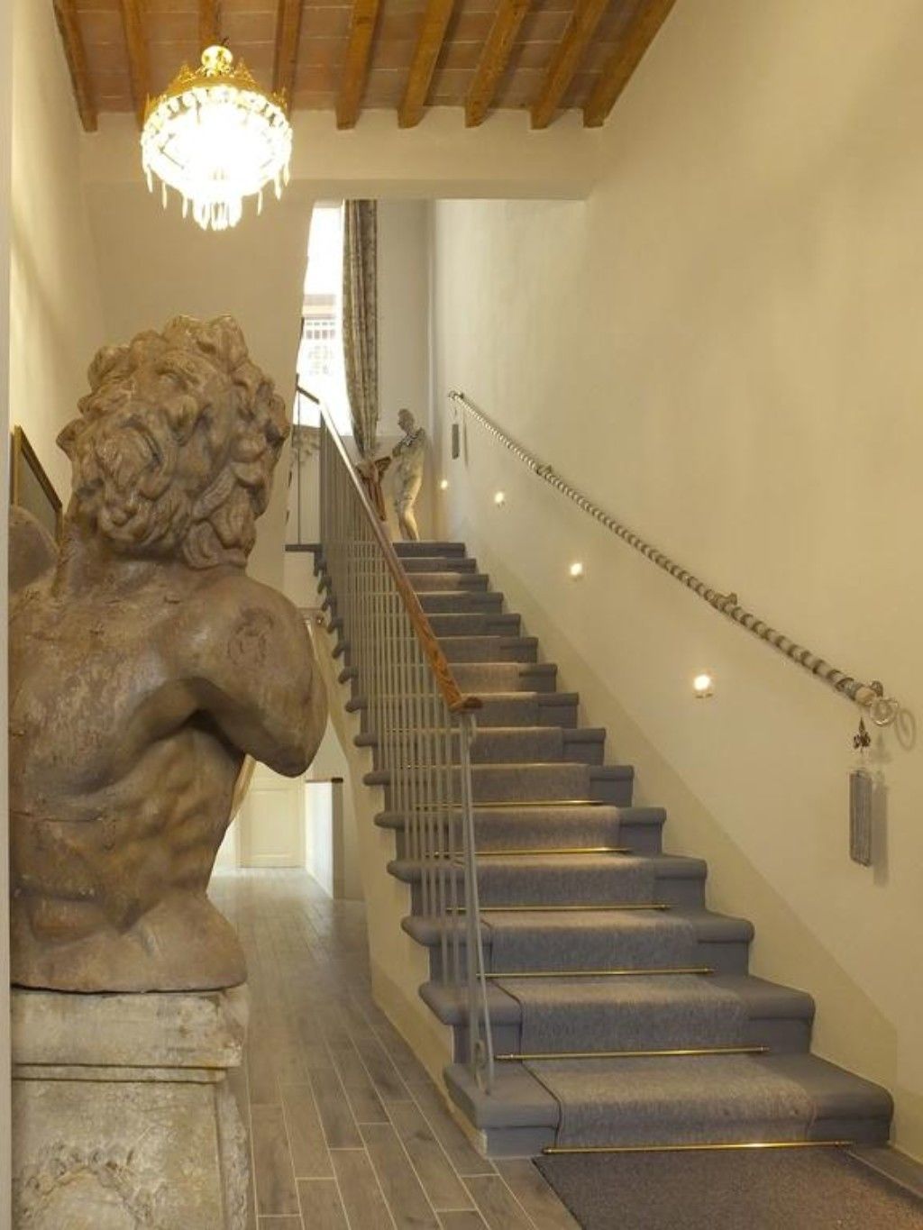 Una escalera con una escultura de león de piedra a la izquierda, un candelabro arriba y una barandilla a la derecha.
