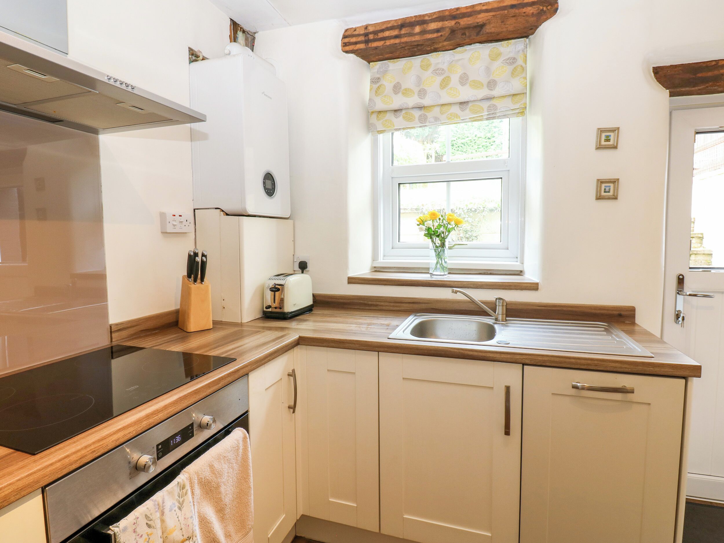 A kitchen with a built-in oven, a toaster, a sink, and a window with a view of greenery.