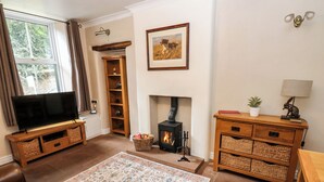 A living room with a television, fireplace, and wooden furniture. - 27 Bongate (Appleby-in-Westmorland)