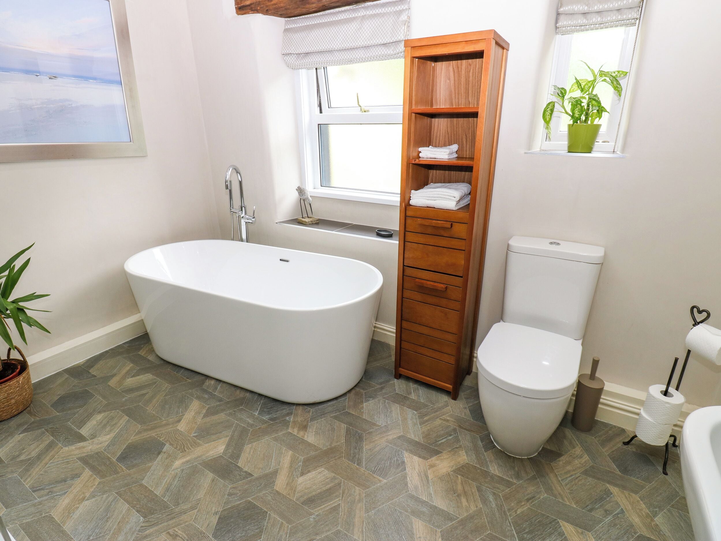Un baño con una bañera independiente, un inodoro y un armario de madera.