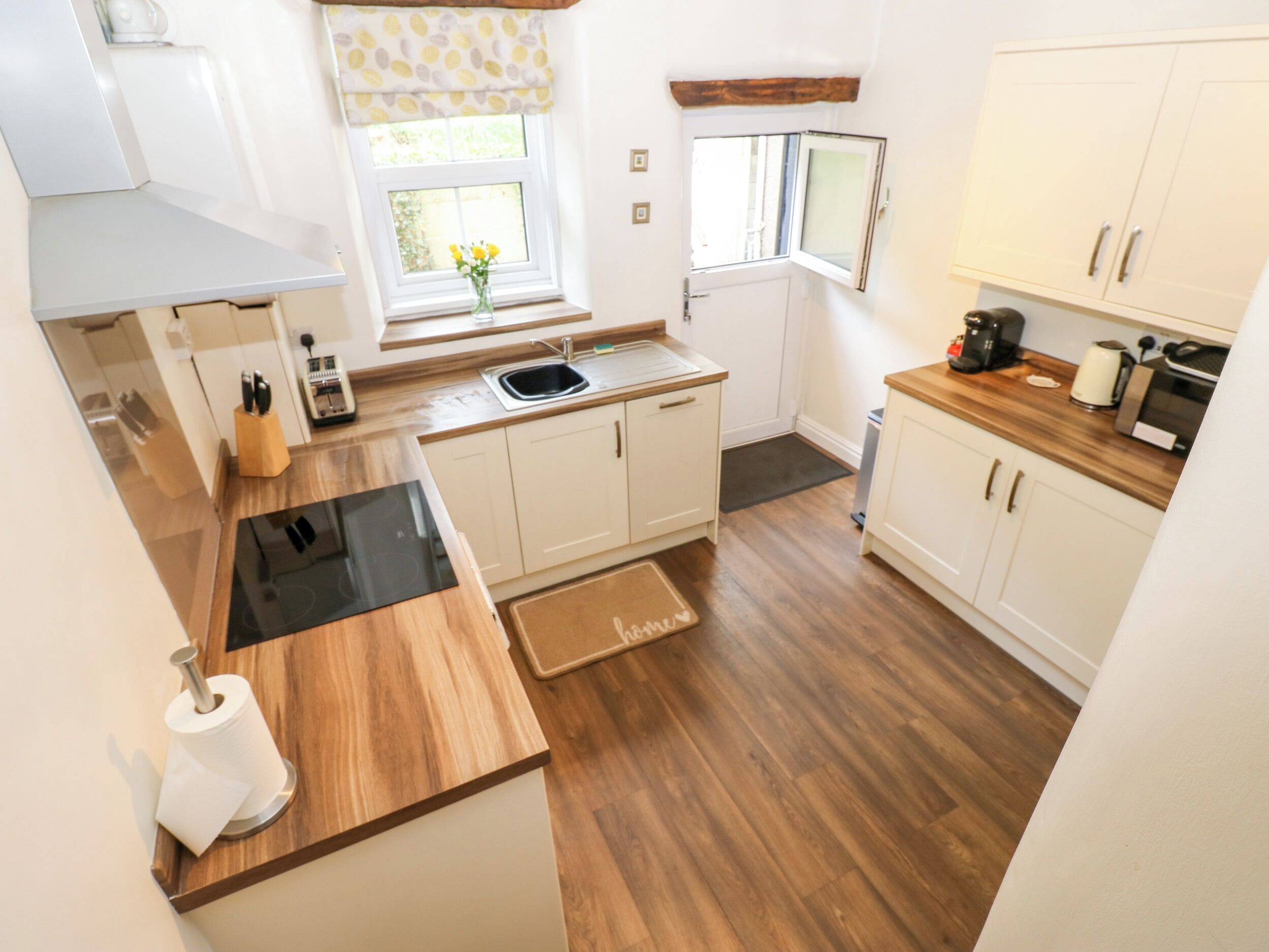 Una cocina moderna con armarios blancos, encimera de madera, estufa integrada y ventana con vistas.