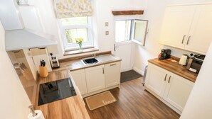 A modern kitchen with white cabinets, a wooden countertop, a built-in stove, and a window with a view. - 27 Bongate (Appleby-in-Westmorland)