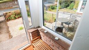 A room with a large window, a wooden bench, and a small table with chairs. - 27 Bongate (Appleby-in-Westmorland)