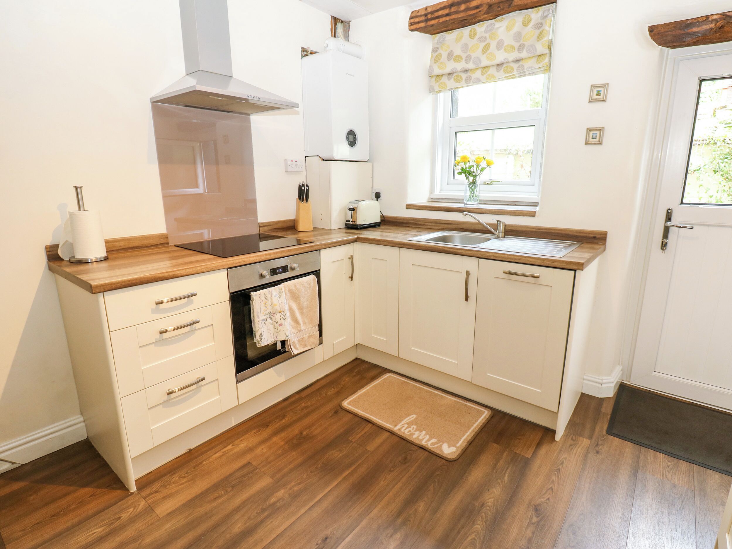 A modern kitchen with a built-in oven, a stainless steel range hood, a sink, and wooden countertops.