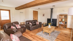 A cozy living room with two brown leather sofas, a wooden coffee table, and a black wood-burning stove. - Pentre Fawr (Llandrindod Wells)