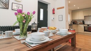Una cocina moderna con armarios blancos, una puerta negra y un comedor con una mesa de madera dispuesta para cuatro.