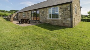 Una casa in pietra con un ampio patio e un tavolo da pranzo.