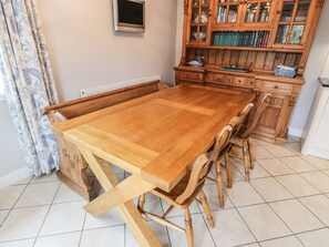 A dining table with chairs, a cabinet with books, and a radiator.